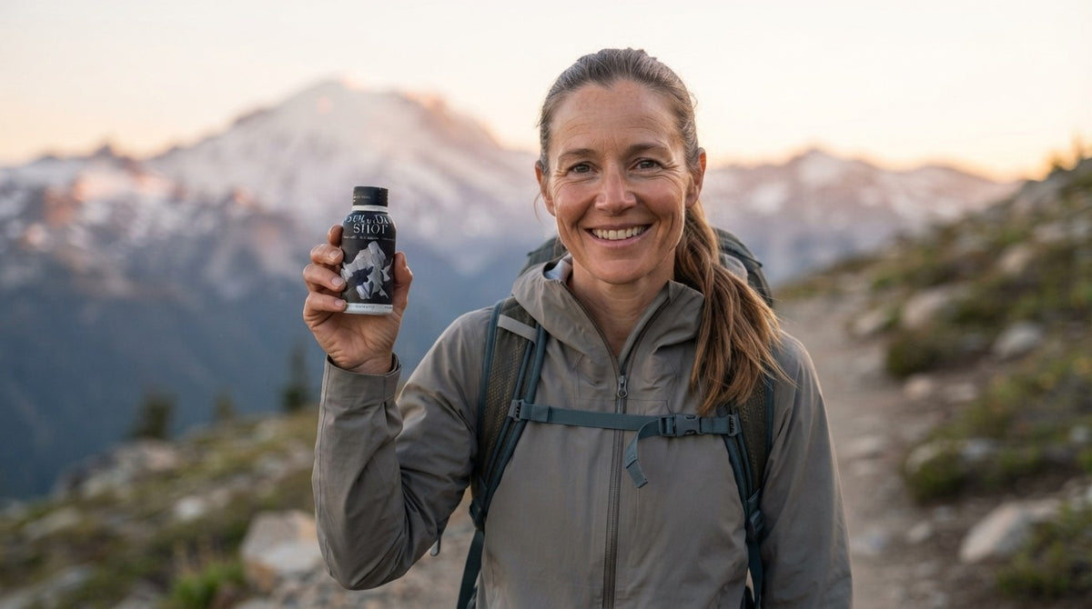Woman on a mountain trail at sunrise holding a Holy Shilajit Shilajit Shot